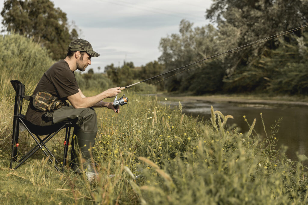 Fishing in Serbia – A scenic view of a fisherman casting a line in a Serbian river at sunset.